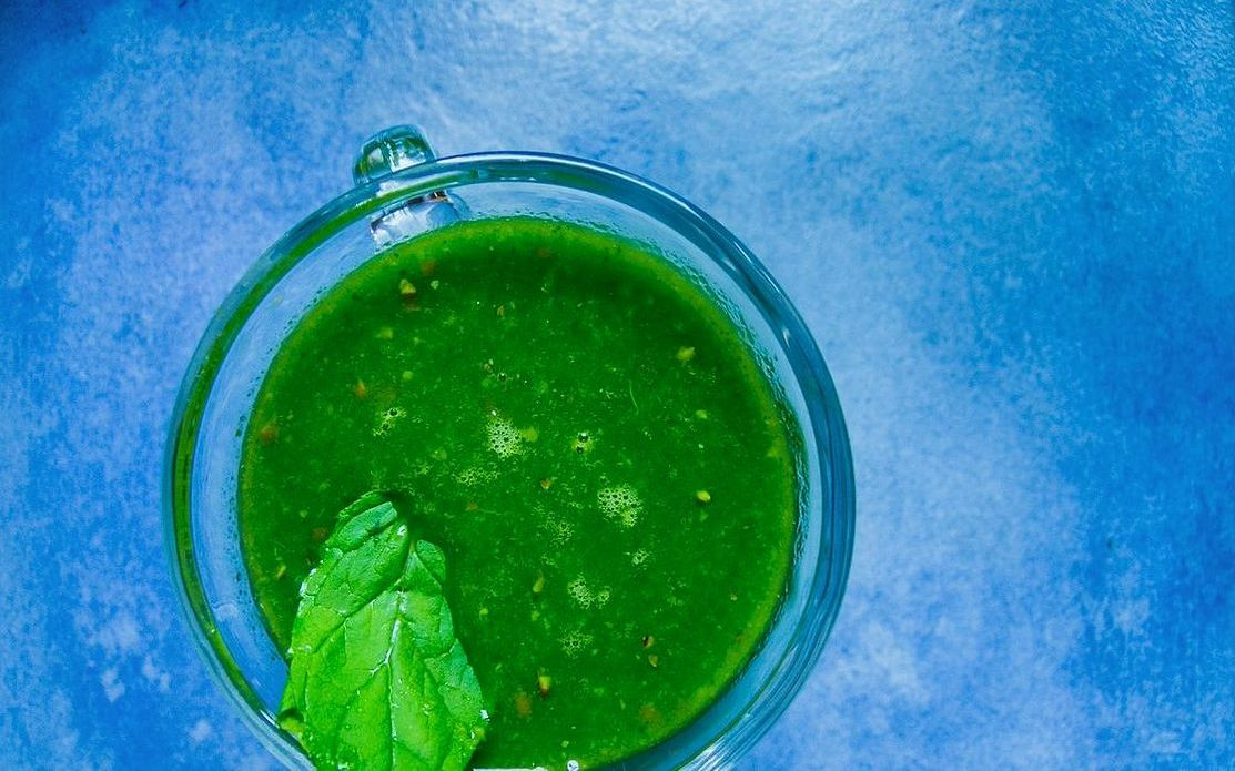 A chilled green juice in a clear glass with ice